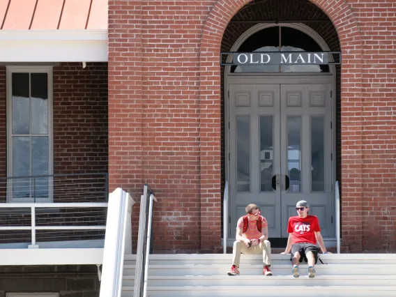 two students sitting on the steps of Old Main