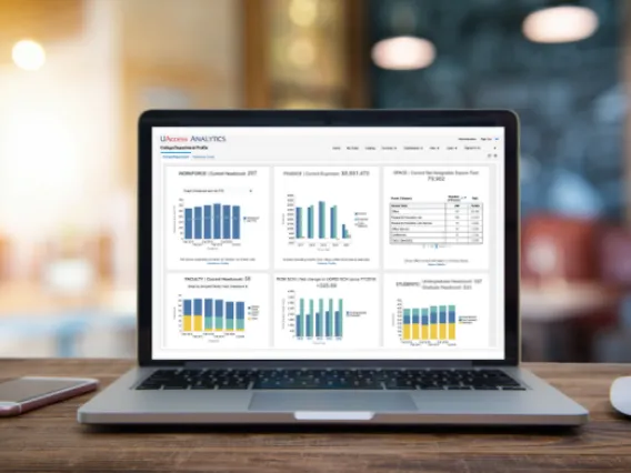 Laptop on a desk showing dashboards from UAccess Analytics