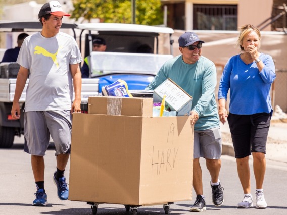 3 people pushing a cardboard box on wheels on move-in day 2023