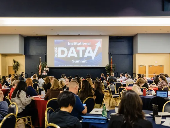 Student Union Grand Ballroom filled with people at tables and a powerpoint on stage that states "2024 Institutional Data Summit"