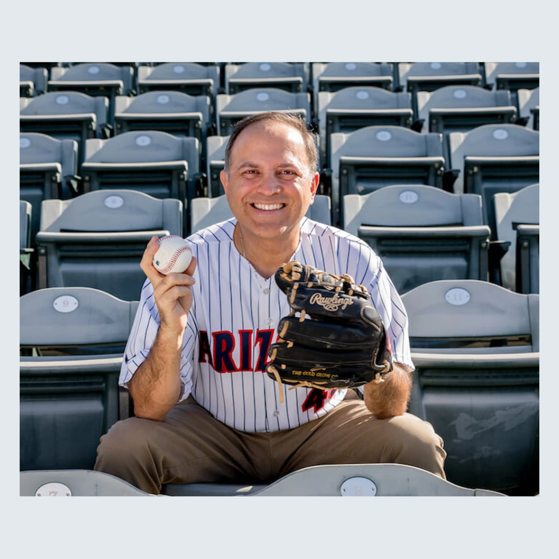 Ricardo Valerdi in baseball stands with an Arizona jersey, a baseball mitt, and baseball