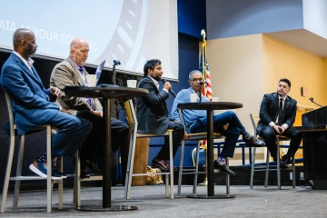 From left to right: Joe Conley, Tim Schwab, Iqbal Hossain (speaking), Nirav Merchant, and Eddie Caratachea on the grand ballroom stage at the summit